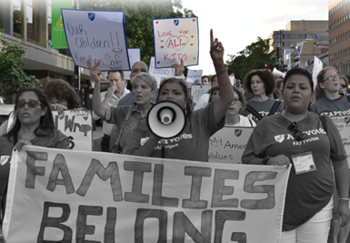 Photo of AFT members marching with AFT Executive Vice President Evelyn DeJesus. Sign reads "Families Belong Together"